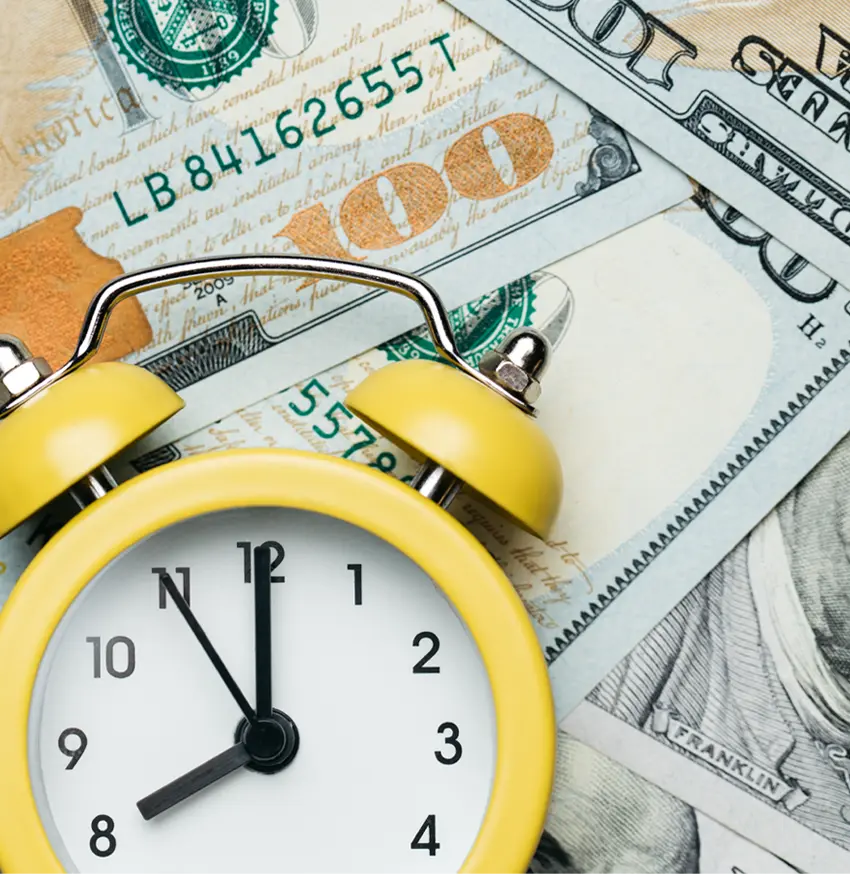 Clock on top of a pile of money.