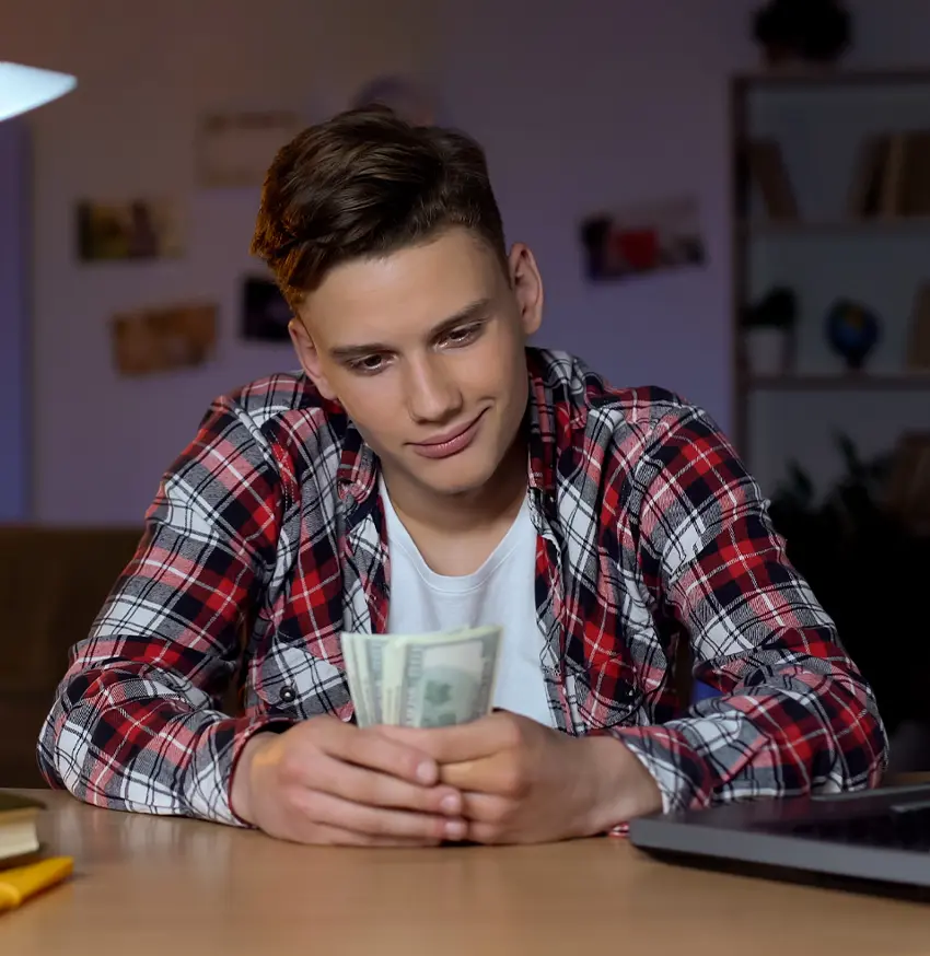 Smiling teen looking at money in hand.