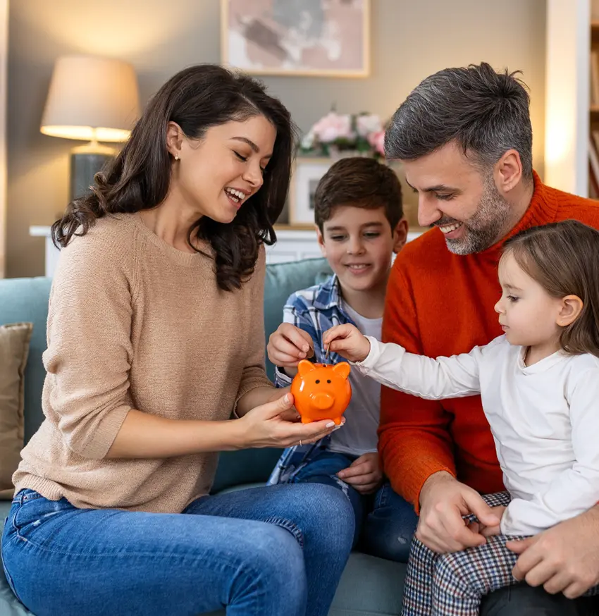 Happy family adding savings to piggy bank.